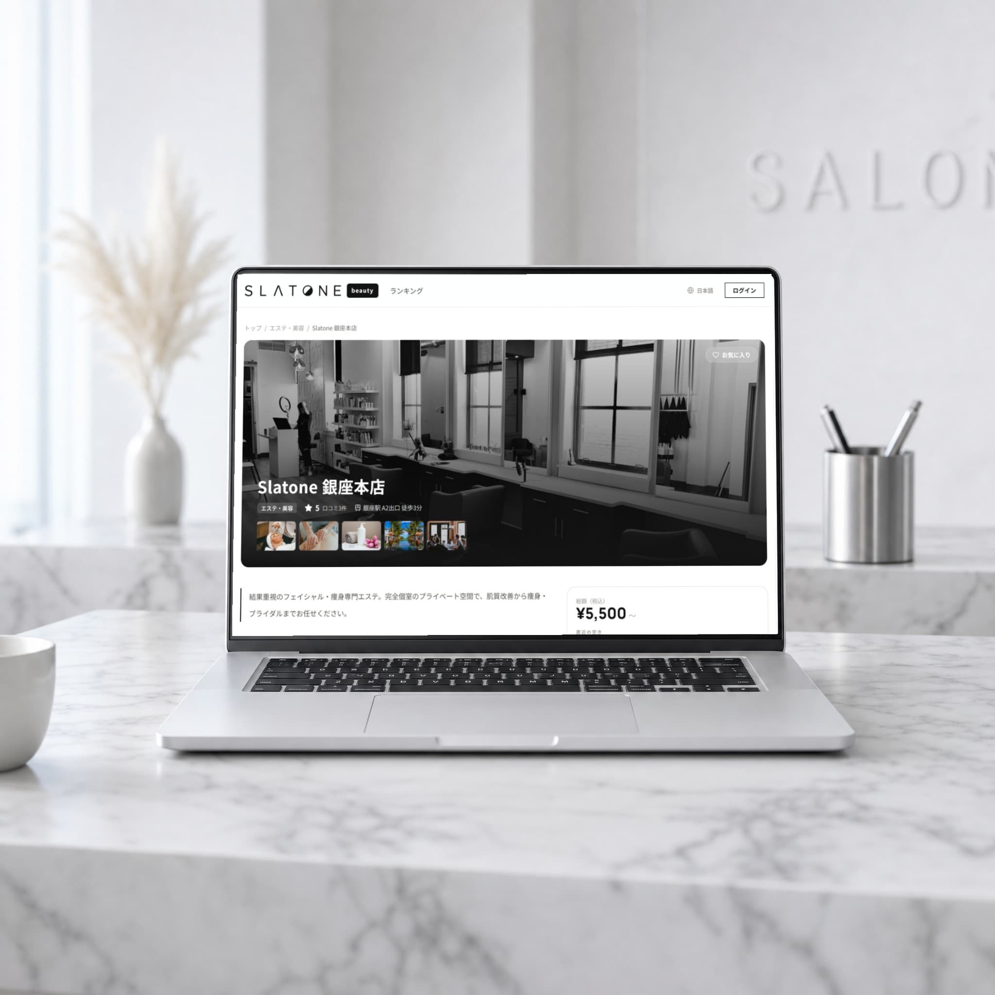 サロンの受付カウンターに置かれたノートPCに、Slatone の店舗ページが表示されている